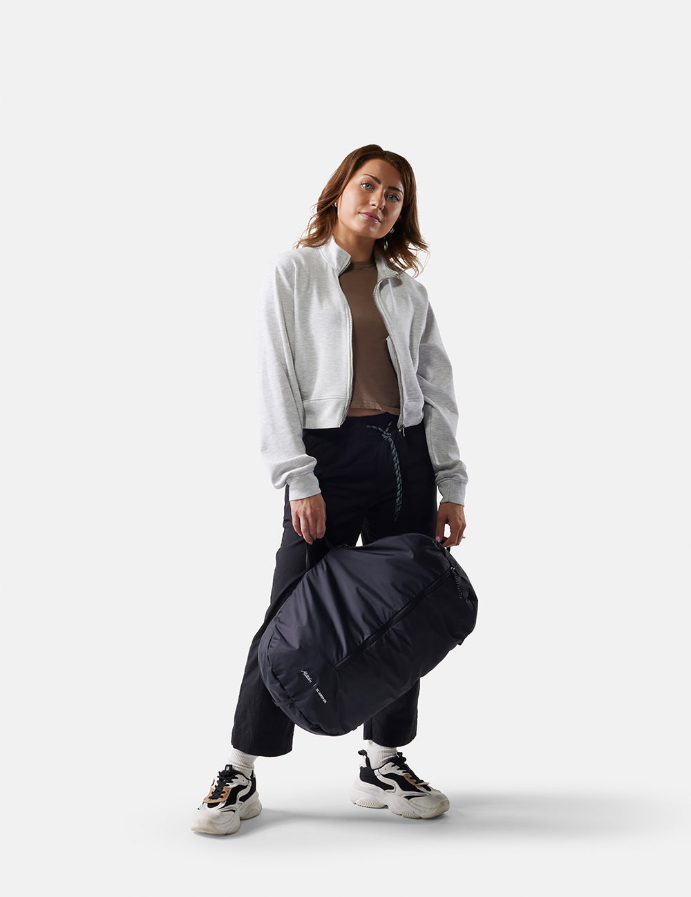 Woman holding a black laundry 
bag against a white background