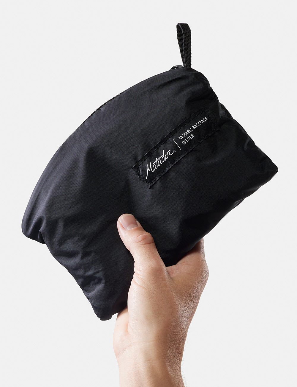 hand on white background holding packed up backpack
